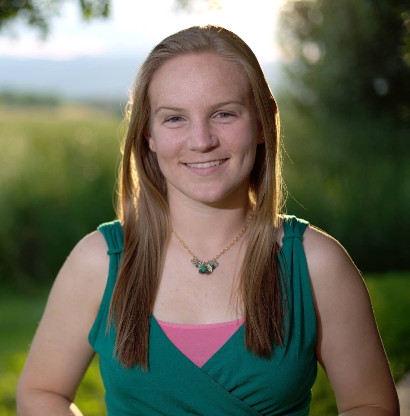 Woman in green top with green necklace smiles into the camera