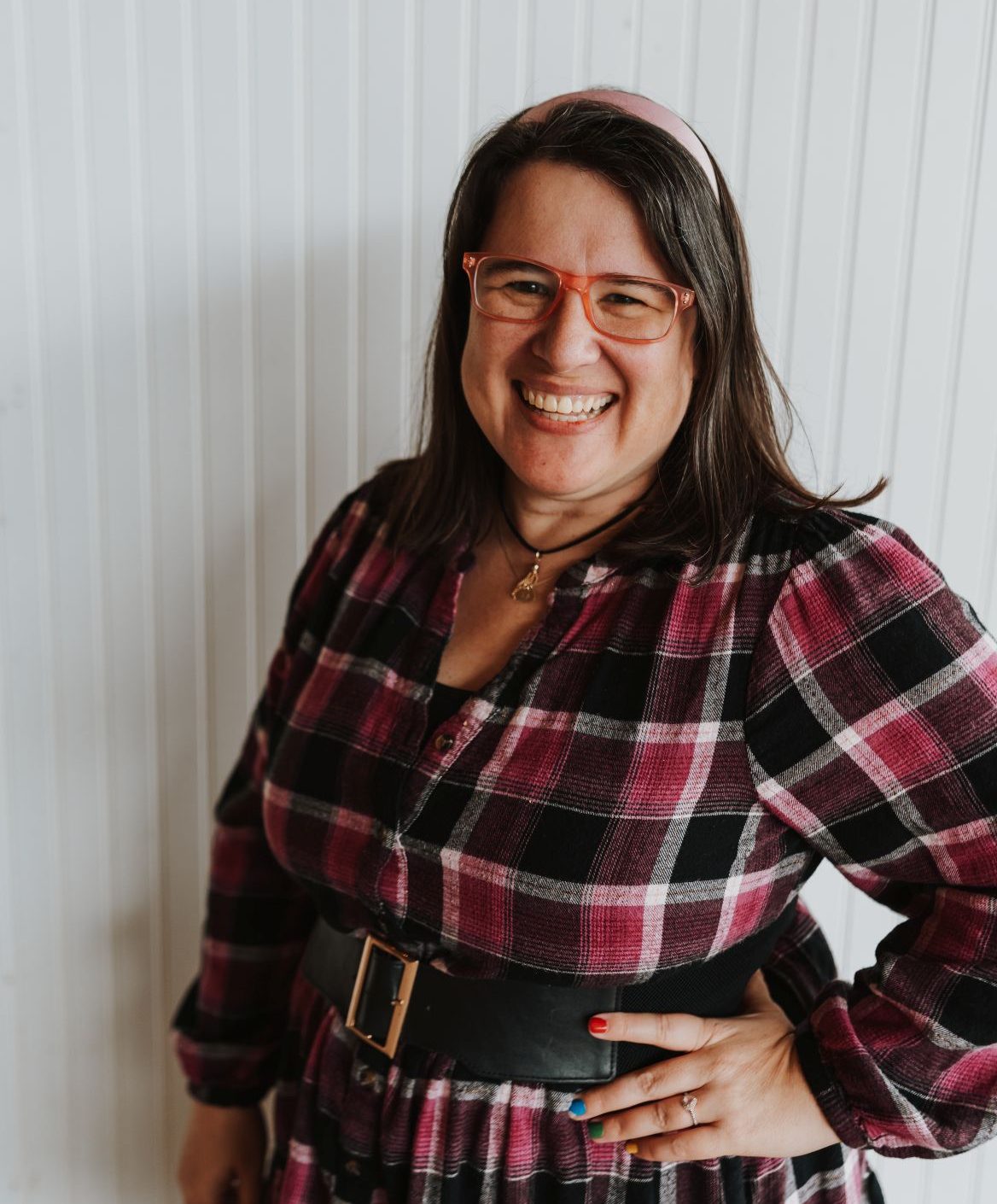 A woman with a pink and black dress smiles into the camera